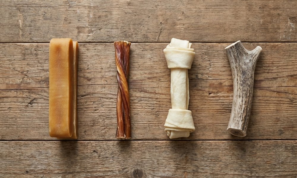 Yak chew beside bully stick, rawhide, and antler for realistic chew comparison.